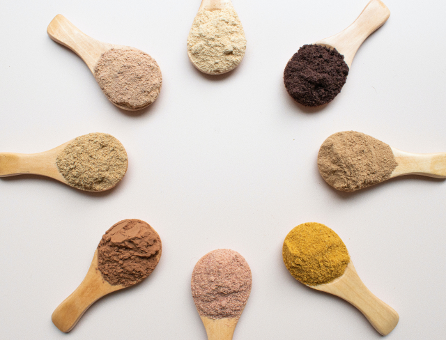 8 wooden spoons in a circle each has it's own addon Cocoa, Cinnamon, Turmeric, Collagen, Bee Pollen, Vegan Protein, Creatine, and Sport Protein.